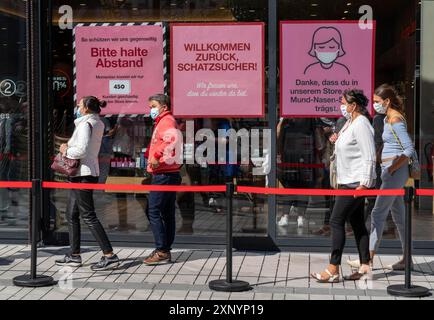 Schlange vor einem Bekleidungsgeschäft, Corona Schutzmaßnahmen, Plakate für Pflichtmasken, Entfernung, Düsseldorf, Nordrhein-Westfalen, Deutschland Stockfoto