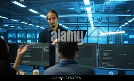 Manager beaufsichtigt multiethnische Teams, die im Rechenzentrum arbeiten, um optimale Leistung zu gewährleisten. Supervisor und Mitarbeiter überwachen den Energieverbrauch über Serverkomponenten hinweg Stockfoto