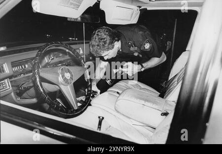 Austin Texas USA, um 1990: Weißer Polizeibeamter durchsucht ein Auto im überwiegend schwarzen Osten von Austin. ©Bob Daemmrich Stockfoto