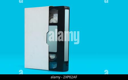 Vorderansicht der alten schwarzen Kunststoff-VHS-Videokassette mit weißem Gehäuse auf blauer Oberfläche vor blauem Hintergrund Stockfoto