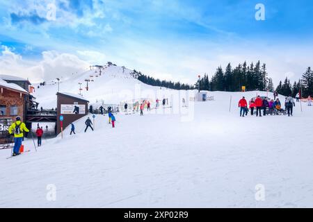 Saalbach, Österreich, 2. März 2020: Skifahrer und Snowboarden auf der Skipiste, Holzrestaurant dahinter Stockfoto