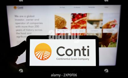 Stuttgart, Deutschland, 03-30-2022: Person, die ein Smartphone mit dem Logo des US-amerikanischen Unternehmens Continental Grain Company (CGC) auf dem Bildschirm vor der Website hält. Stockfoto