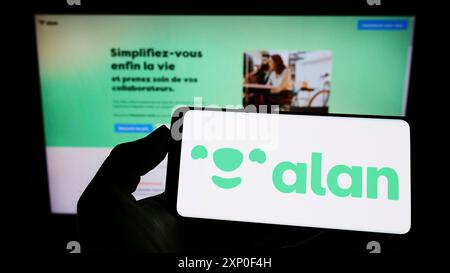 Stuttgart, Deutschland, 03-30-2022: Person mit Handy mit Logo der französischen Krankenkasse Alan SA auf dem Bildschirm vor der Unternehmenswebseite. Stockfoto
