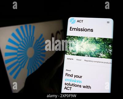 Stuttgart, Deutschland, 04.03.2022: Person, die ein Mobiltelefon hält, mit Webseite der niederländischen Firma ACT Commodities Group BV vor dem Logo. Konzentrieren Sie sich auf Stockfoto