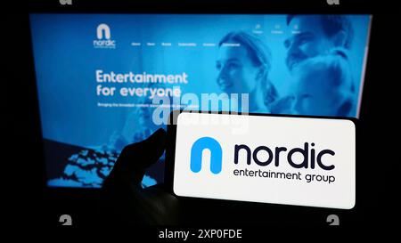 Stuttgart, Deutschland, 28.03.2022: Person mit Smartphone mit Logo des schwedischen Unternehmens Nordic Entertainment Group ab (NENT) vor dem Bildschirm Stockfoto