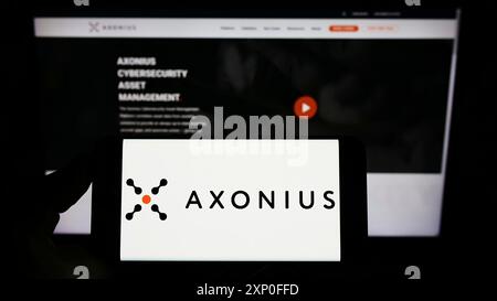 Stuttgart, Deutschland, 03.12.2022: Person, die ein Mobiltelefon mit dem Logo des US-amerikanischen Cybersicherheitsunternehmens Axonius Inc. Auf dem Bildschirm vor der Unternehmenswebseite hält. Stockfoto