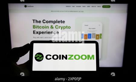 Stuttgart, Deutschland, 03.12.2022: Person, die ein Mobiltelefon mit dem Logo der US-amerikanischen Kryptobörse CoinZoom Inc. Auf dem Bildschirm vor dem Geschäft hält Stockfoto