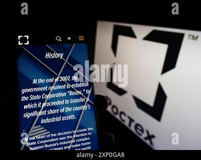 Stuttgart, Deutschland, 05-08-2022: Person, die ein Handy hält, mit Webseite der russischen Verteidigungsfirma Rostec vor dem Geschäftslogo. Konzentrieren Sie sich auf Stockfoto