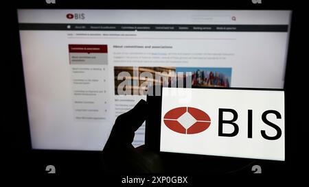 Stuttgart, Deutschland, 03-01-2022: Person mit Mobiltelefon mit Logo der Bank für Internationalen Zahlungsausgleich (BIZ) vor dem Geschäft Stockfoto