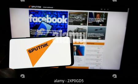 Stuttgart, Deutschland, 03.01.2022: Person mit Handy mit Logo des russischen staatlichen Medienunternehmens Sputnik auf dem Bildschirm vor der Webseite. Konzentrieren Sie sich auf Stockfoto