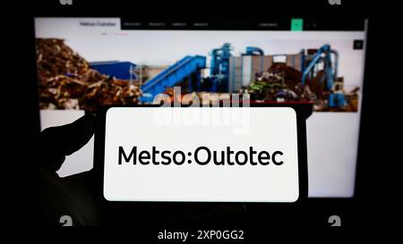 Stuttgart, Deutschland, 26.02.2022: Person, die ein Mobiltelefon mit dem Logo des finnischen Maschinenbauunternehmens Metso Outotec Oyj auf dem Bildschirm vor dem Geschäft hält Stockfoto