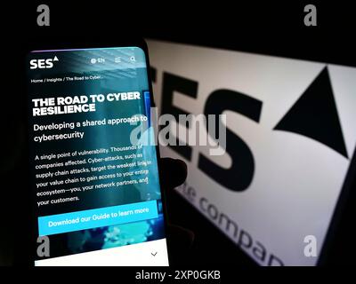 Stuttgart, Deutschland, 26.02.2022: Person, die ein Smartphone hält, mit der Webseite des Satelliten-Telekommunikationsunternehmens SES S.A. auf dem Bildschirm mit Logo. Konzentrieren Sie sich auf Stockfoto