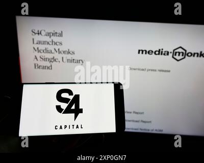 Stuttgart, Deutschland, 26.02.2022: Person, die ein Mobiltelefon mit dem Logo der britischen Werbefirma S4 Capital plc vor dem Geschäft hält Stockfoto