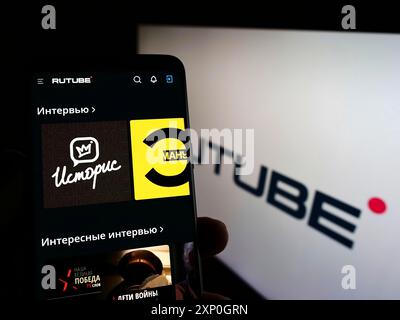 Person, die ein Handy hält, mit der Webseite der russischen Videoplattform Rutube vor dem Logo auf dem Bildschirm. Konzentrieren Sie sich auf die Mitte des Telefondisplays Stockfoto