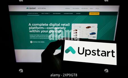 Person mit Smartphone und Logo des US-amerikanischen Fintech-Unternehmens Upstart Network Inc. Auf dem Bildschirm vor der Website. Schwerpunkt auf dem Display des Telefons Stockfoto