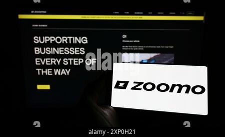 Stuttgart, Deutschland, 26.02.2022: Person, die ein Mobiltelefon mit dem Logo des Elektrofahrradunternehmens Bolt Bikes (Zoomo) vor dem Geschäft hält Stockfoto