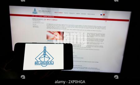 Stuttgart, Deutschland, 02-11-2022: Person, die ein Mobiltelefon mit dem Logo des belarussischen Kaliunternehmens Belaruskali auf dem Bildschirm vor der Website der Geschäftswelt hält. Stockfoto