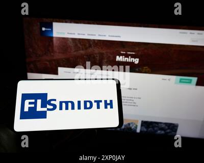 Stuttgart, Deutschland, 01-30-2022: Person mit Mobiltelefon mit Logo der dänischen Ingenieurin FLSmidth Co. WIE auf dem Bildschirm vor der Business-Website. Stockfoto