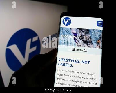 Stuttgart, Deutschland, 28.01.2022: Person, die ein Mobiltelefon hält, mit Webseite des US-Bekleidungsunternehmens VF Corporation auf dem Bildschirm vor dem Firmenlogo. Fokus Stockfoto