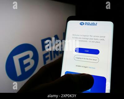 Stuttgart, Deutschland, 23.01.2022: Person, die ein Smartphone hält, mit Webseite des indischen Finanzunternehmens Bajaj FinServ Limited auf dem Bildschirm mit Logo. Fokus Stockfoto