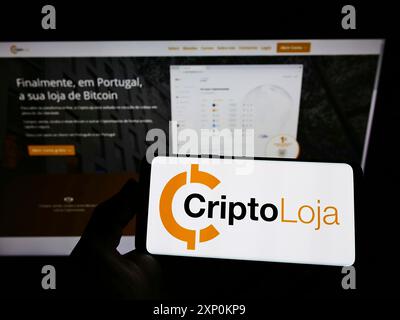 Stuttgart, Deutschland, 16.01.2022: Person mit Smartphone und Logo des portugiesischen Unternehmens Smart Token Lda. (CriptoLoja) vor dem Bildschirm Stockfoto