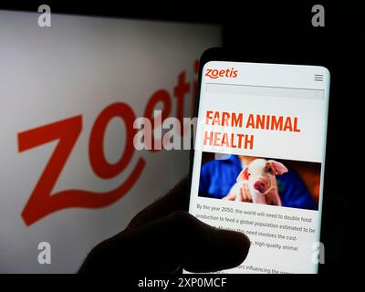 Stuttgart, Deutschland, 01.06.2022: Person, die ein Mobiltelefon hält, mit Webseite des US-amerikanischen Tierarzneimittelunternehmens Zoetis Inc. Auf dem Bildschirm vor dem Firmenlogo. Stockfoto