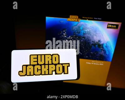 Stuttgart, Deutschland, 01-08-2022: Person, die ein Smartphone mit dem Logo der transnationalen europäischen Lotterie Eurojackpot auf dem Bildschirm vor der Website hält. Stockfoto