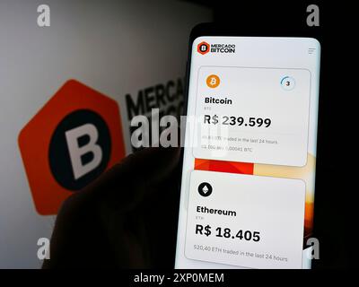 Stuttgart, Deutschland, 01-08-2022: Person, die ein Smartphone mit Webseite der Firma Mercado Bitcoin Servicos Digitais Ltda hält. Auf dem Bildschirm mit Logo. Fokus Stockfoto