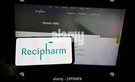 Stuttgart, Deutschland, 01-08-2022: Person, die ein Mobiltelefon mit dem Logo des schwedischen Pharmazeutischen Recipharm ab auf dem Bildschirm vor der Unternehmenswebseite hält. Stockfoto