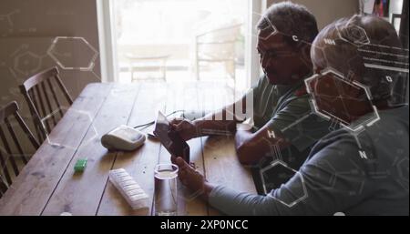 Chemisches Strukturbild über älteres Ehepaar mit Tablette am Holztisch Stockfoto