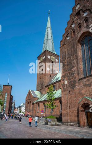 Kirchturm der Kathedrale von Aarhus mit Leuten, die bei schönem Wetter vor der Tür laufen, vertikale Aufnahme Stockfoto