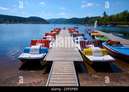 Eine malerische Szene mit bunten Tretbooten und Holzbooten auf einem Bootssteg vor dem Schluchsee, umgeben von Bergen, Frühling, Schluchsee Stockfoto