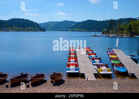 Eine malerische Szene mit bunten Tretbooten und Holzbooten auf einem Bootssteg vor dem Schluchsee, umgeben von Bergen, Frühling, Schluchsee Stockfoto