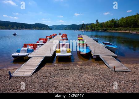 Eine malerische Szene mit bunten Tretbooten und Holzbooten auf einem Bootssteg vor dem Schluchsee, umgeben von Bergen, Frühling, Schluchsee Stockfoto