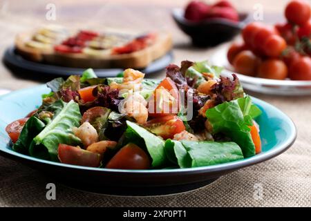 Ein lebhaftes, verführerisches Frühstück mit bunten Salaten, Garnelen, Reifen Tomaten, Sandwiches, Bananen, frische Erdbeeren. Gesunde Mahlzeit bietet ein köstliches Nutri Stockfoto