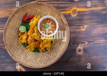 Knusprige Teigtaschen in Hühnchen, Gemüse und Gewürzen werden auf einem weißen Teller serviert, der auf einem Holztisch im Restaurant steht. Gebratene Knödel Stockfoto