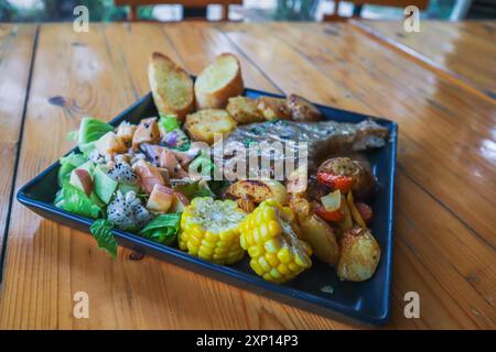 Fruchtsalat ist ein Dessert aus verschiedenen Obstscheiben, garniert mit einem Dressing und serviert auf einem großen Steakteller für Gäste Stockfoto