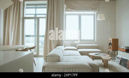 Moderne Inneneinrichtung mit offenem Raum mit verstellbarem Sofa, Möbeln, hölzernen Kaffeetischen, gemusterten Bettüberwürfen, Kissen, und stilvoller persönlicher Zugang Stockfoto