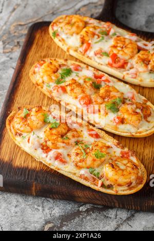 Heiß gebackene Sandwiches mit Garnelen, Käse, Knoblauch und Tomaten aus nächster Nähe auf einem Holzbrett auf dem Tisch. Vertikal Stockfoto