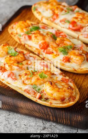 Cheesy Shrimp Knoblauch Brot mit Kräutern und Tomaten Nahaufnahme auf dem Holzbrett auf dem Tisch. Vertikal Stockfoto