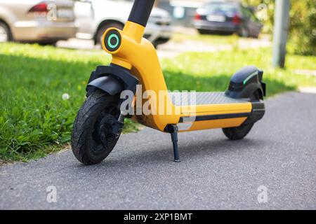 Ein leuchtend gelber Roller parkt ordentlich am Straßenrand und wartet darauf, dass der Besitzer zurückkehrt und sich im Sonnenlicht sonnt Stockfoto