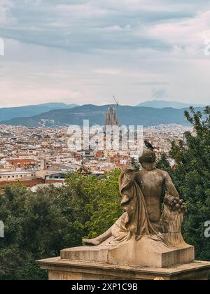 Eine Statue einer Frau sitzt auf einem Podest vor einer Stadt. Die Statue ist von Bäumen umgeben und die Skyline der Stadt im Hintergrund. Friedensbegriff Stockfoto