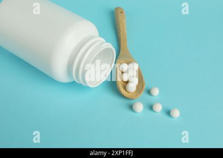 Homöopathie. Flasche und Löffel mit Pillen auf hellblauem Hintergrund Stockfoto