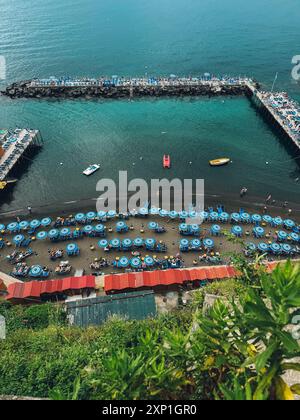 Ein Strand mit vielen Sonnenschirmen und Booten. Der Strand ist voll mit Menschen und das Wasser ist ruhig Stockfoto
