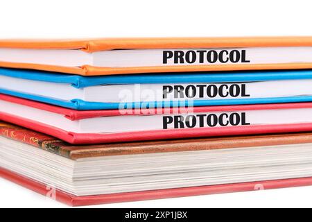 Ein Word PROTOCOL, das auf den Enden von Notizbüchern geschrieben ist, die auf weißem Hintergrund übereinander liegen Stockfoto