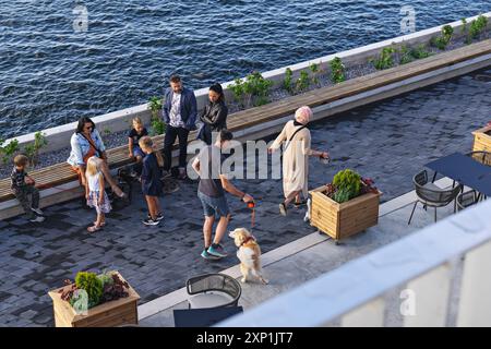 Verschiedene Gruppen von Menschen, darunter Kinder und Erwachsene, gehen und interagieren mit einem Hund auf einer Strandpromenade im Tallinn Kreuzfahrthafen: Tallinn, Estoni Stockfoto