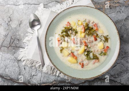 Traditionelle Zuppa Toscana oder toskanische Suppe mit italienischer Wurst, Grünkohl, gebratenem Speck und Kartoffeln aus der Nähe auf dem Teller auf dem Tisch. Horizontale Draufsicht f Stockfoto