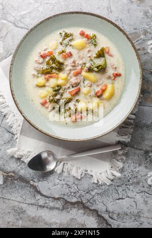 Wurst und Grünkohl Zuppa toscana italienische cremige Suppe Nahaufnahme auf dem Teller auf dem Tisch. Vertikale Draufsicht von oben Stockfoto