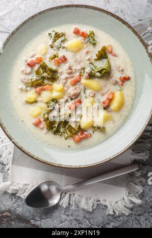 Toskanische Suppe mit italienischen Würstchen, Grünkohl, Kartoffeln, Zwiebeln und Knoblauch auf dem Teller auf dem Tisch. Vertikale Draufsicht von oben Stockfoto