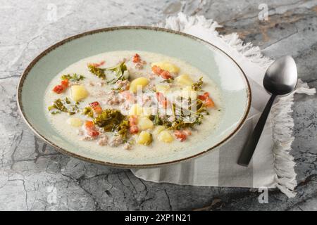 Traditionelle Zuppa Toscana oder toskanische Suppe mit italienischer Wurst, Grünkohl, gebratenem Speck und Kartoffeln aus der Nähe auf dem Teller auf dem Tisch. Horizontal Stockfoto